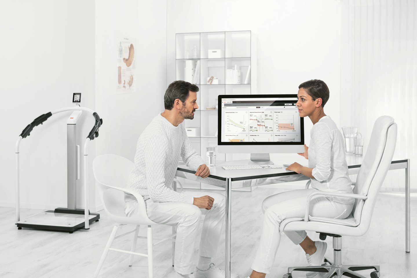 Woman consults with man over health data on computer.